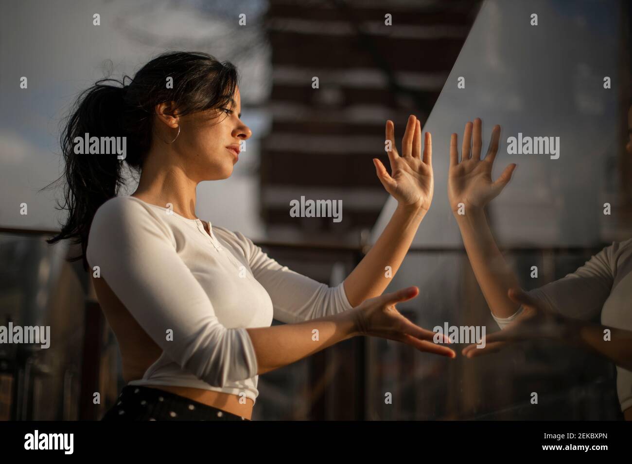 Mid adult woman gesturing while looking through glass Stock Photo