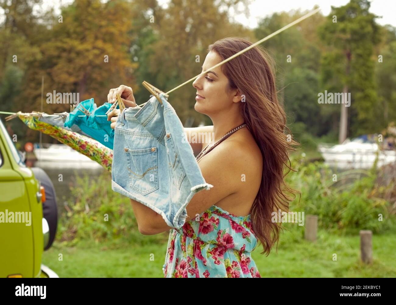 Young woman hanging out washing clothes on clothesline by camper van Stock Photo