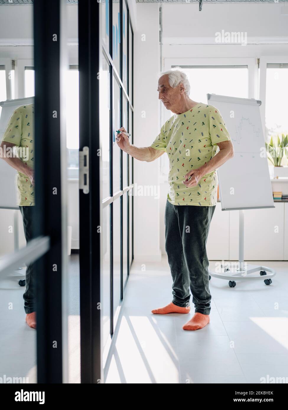 Senior entrepreneur writing in glass wall while standing at office Stock Photo
