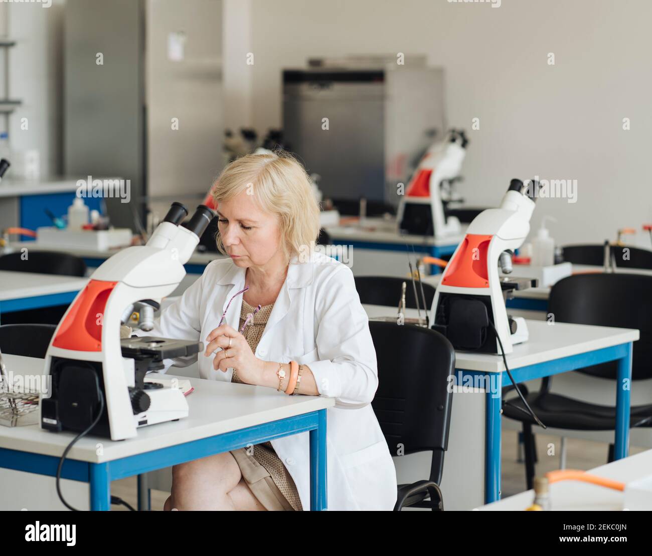 Senior female researcher in a white coat working in lab Stock Photo