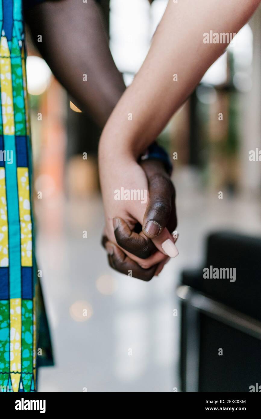 Young man and woman holding hands while standing outdoors Stock Photo