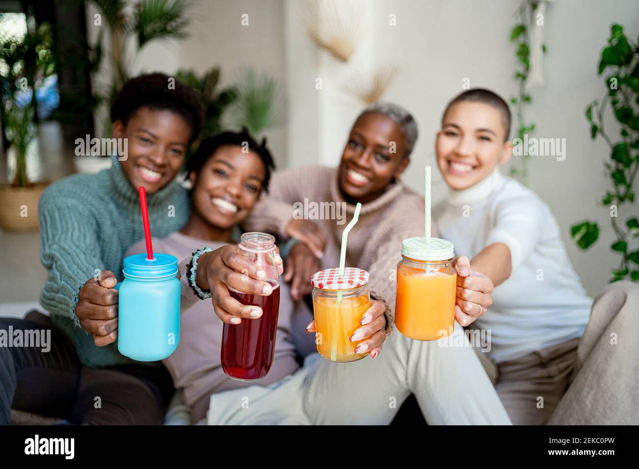Multi-ethnic female friends holding juice at home Stock Photo