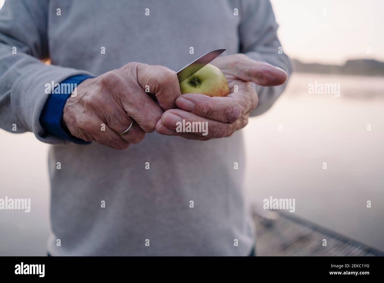 Man cutting apple while standing outdoors Stock Photo