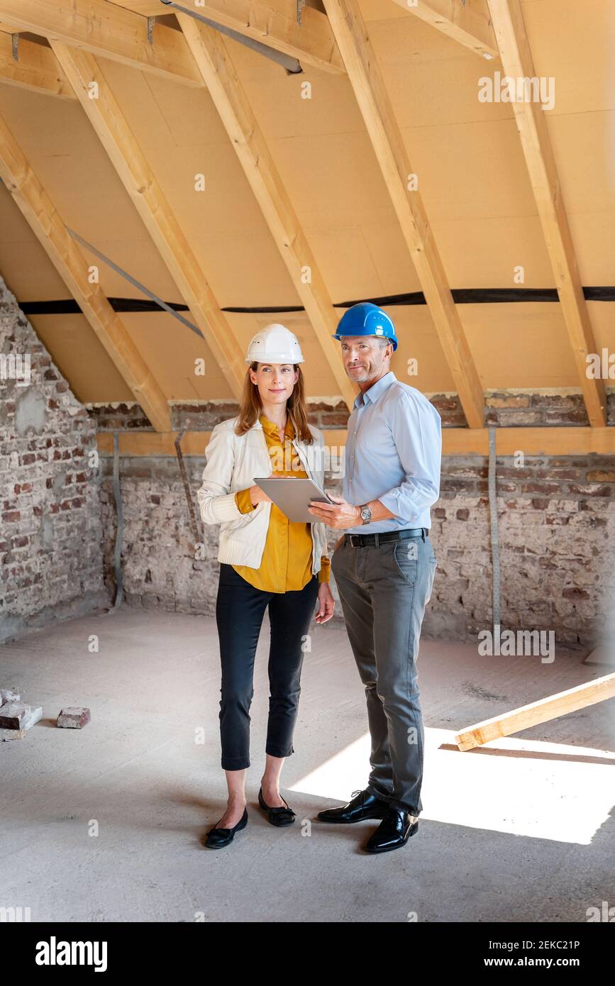 Professional team wearing hardhat working while standing with digital tablet at construction site Stock Photo