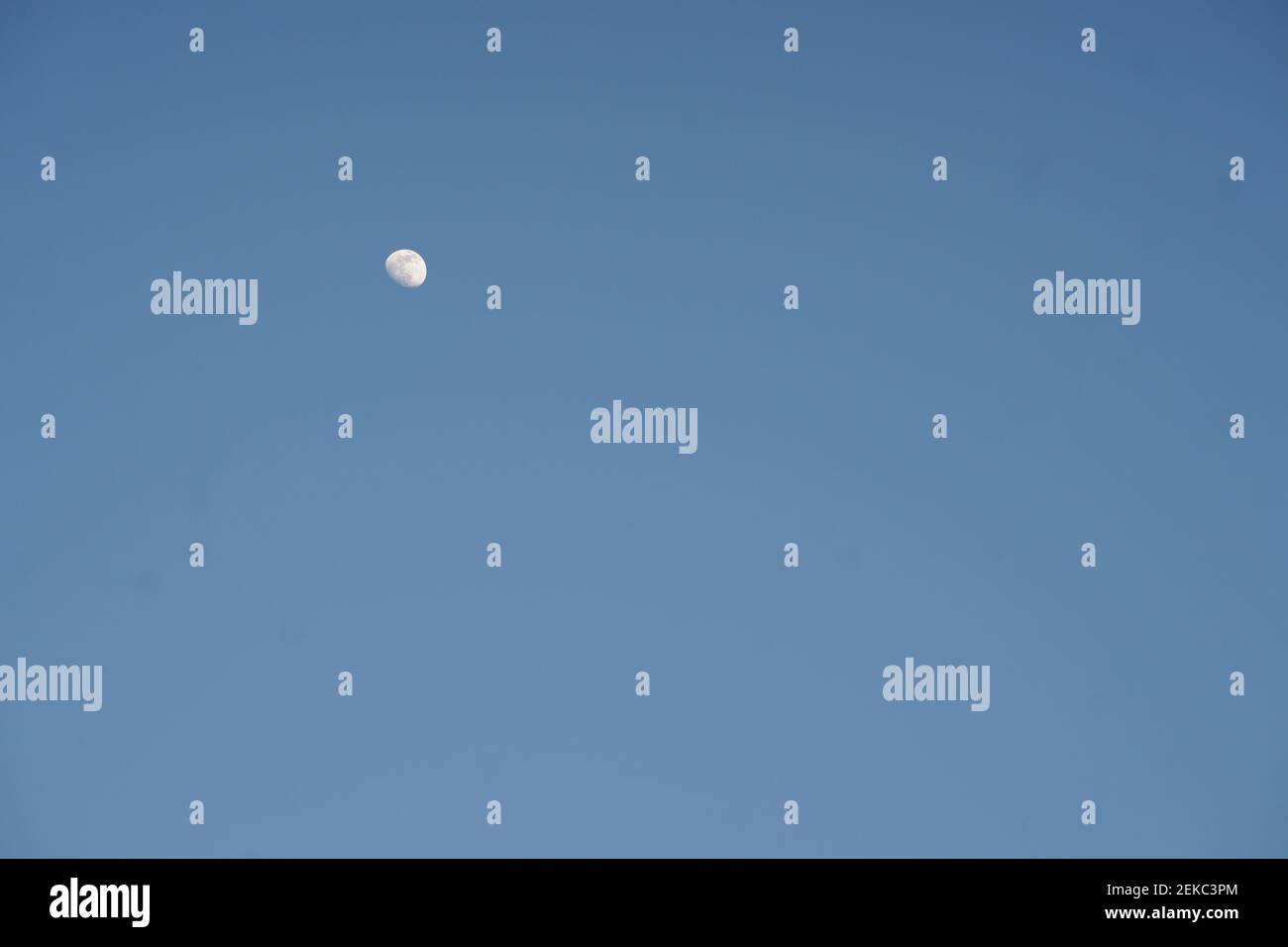 growing moon in clear blue sky during the day. Stock Photo