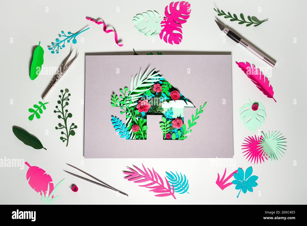 Paper craft of Eco home with plants and flowers amidst scraps on white background Stock Photo