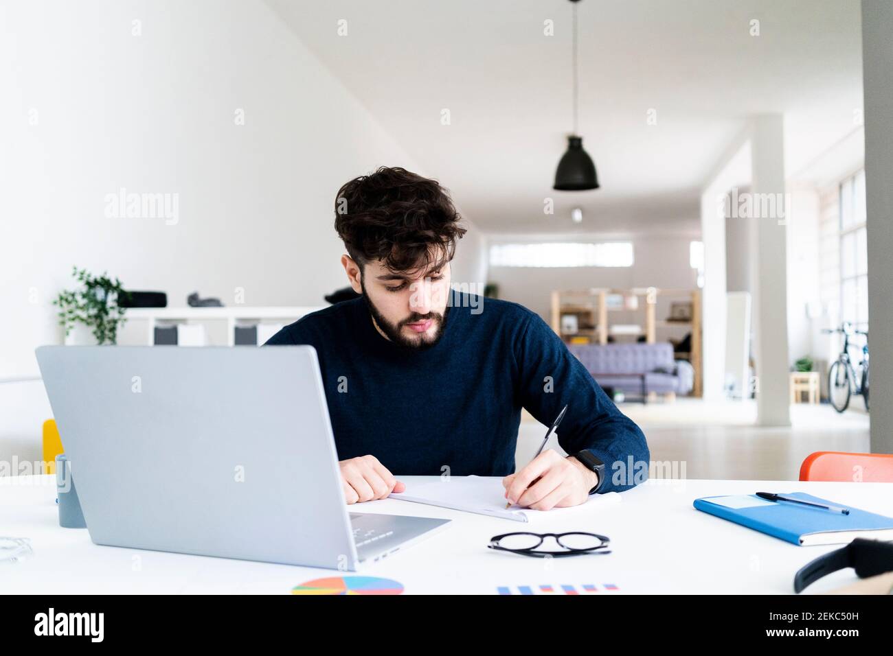Young businessman writing at desk in creative office Stock Photo