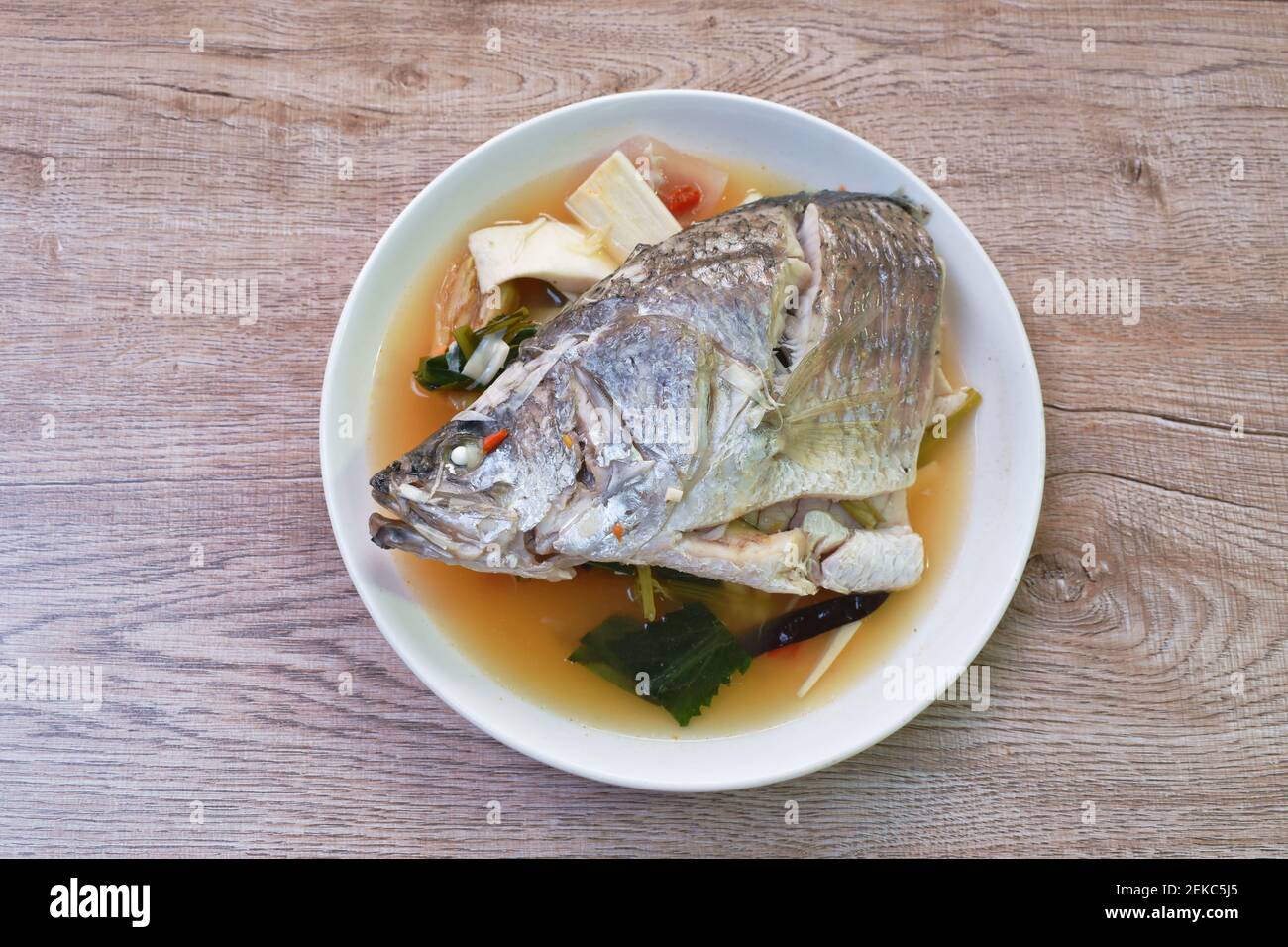 spicy bass fish head and slice coconut shoot in Tom Yum soup on plate