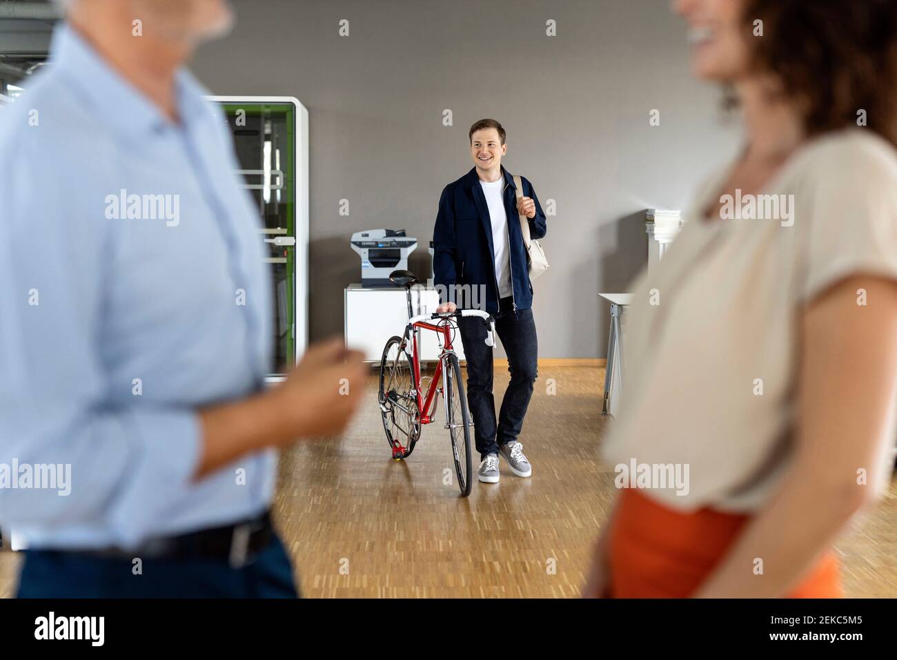 Business people standing with colleague in background holding bag while leaving after work from office Stock Photo