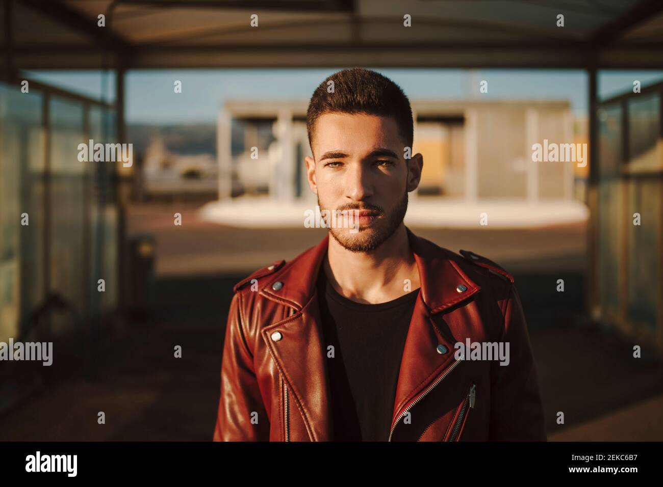 Fashionable man wearing red leather jacket staring while standing at car wash station Stock Photo