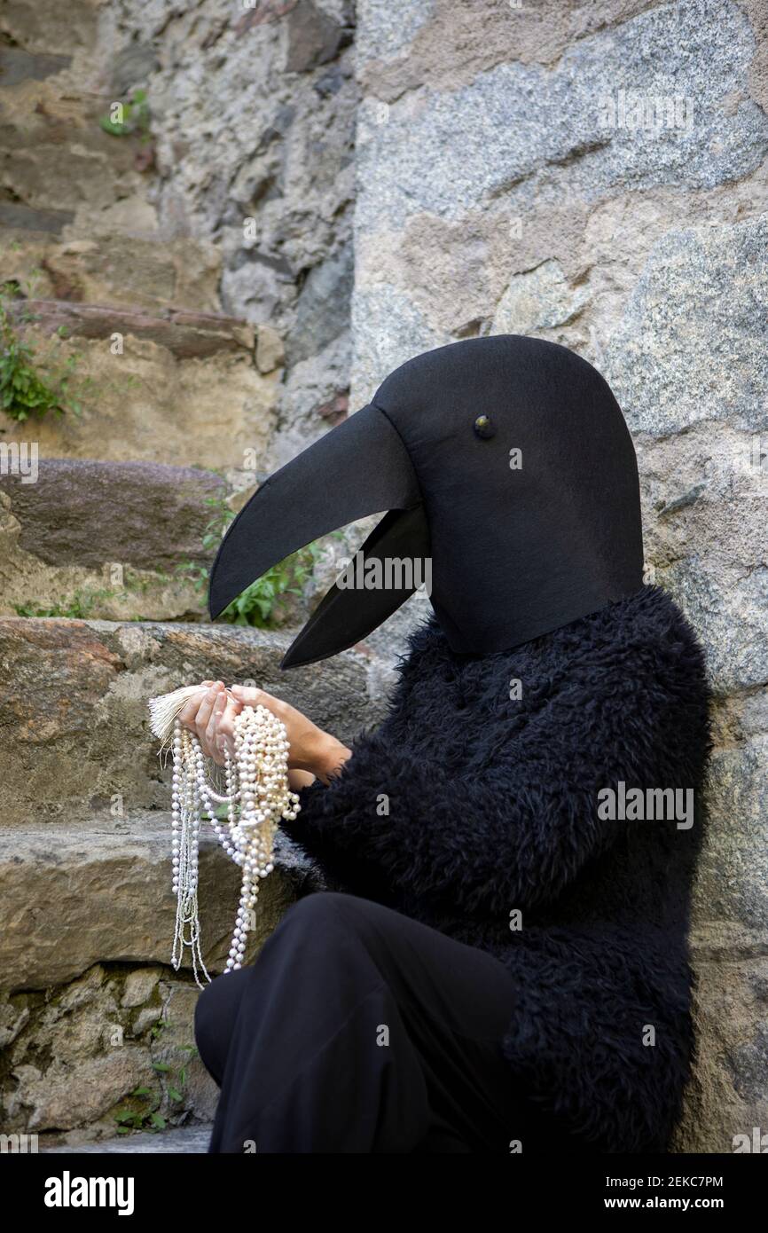 Woman in crow costume looking at jewelry by staircase Stock Photo