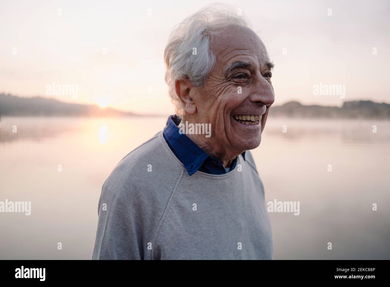 Happy man looking away while standing against lake Stock Photo