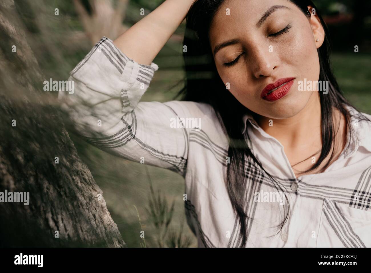 Beautiful woman with eyes closed at public park Stock Photo
