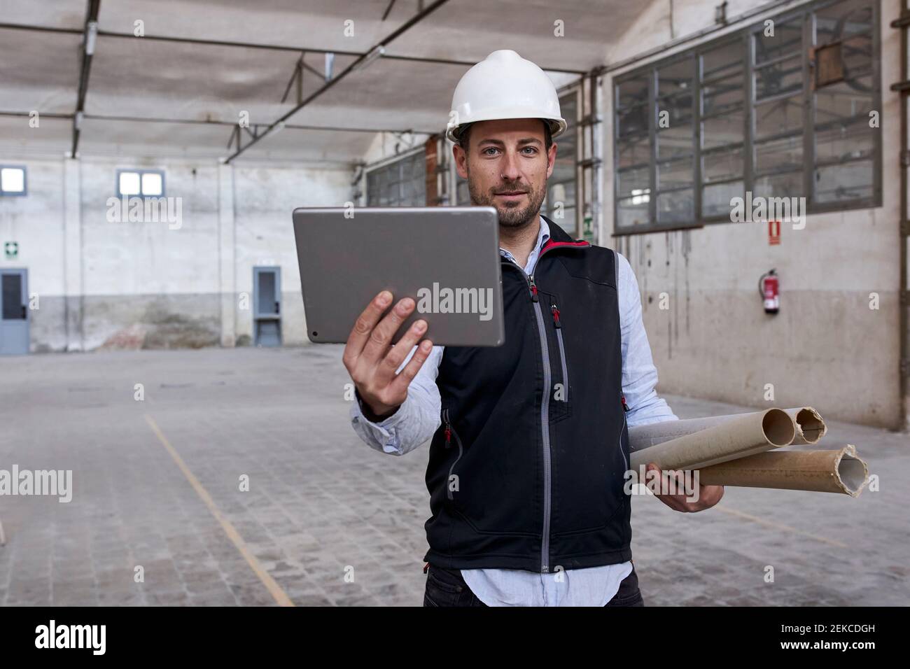 Male engineer using digital tablet while working in building at construction site Stock Photo