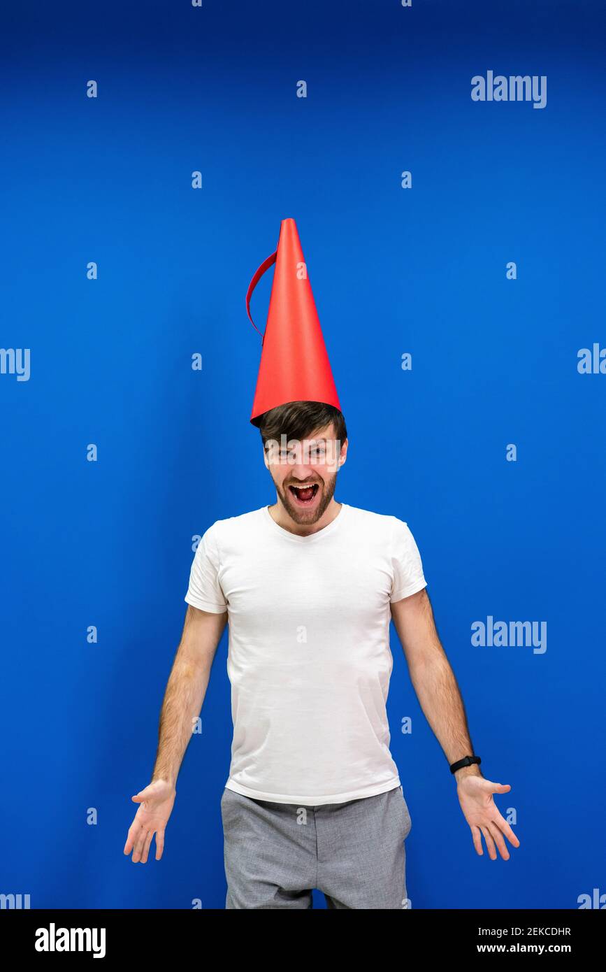 Cheerful male professional wearing cone shaped megaphone on head