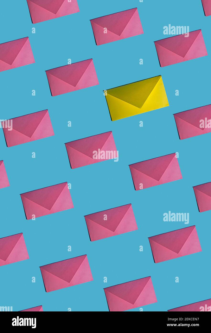 Pattern of rows of pink envelopes with single yellow one Stock Photo