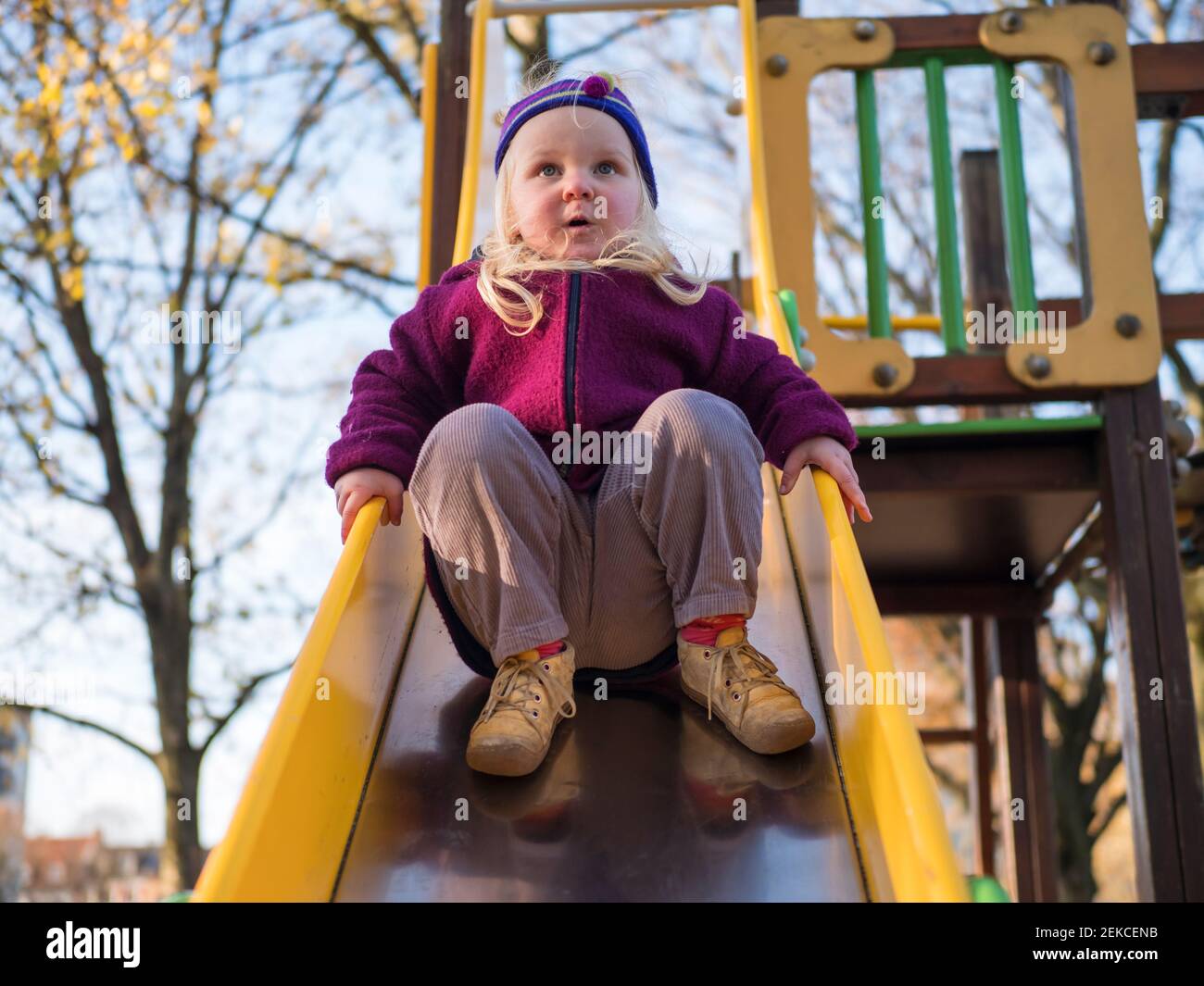 Cute girl playing on slide at playground Stock Photo - Alamy