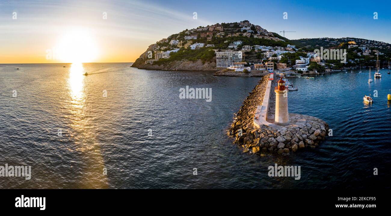 Spain, Balearic Islands, Andratx, Helicopter view of coastal town and Port D Andratx Lighthouse at sunset Stock Photo