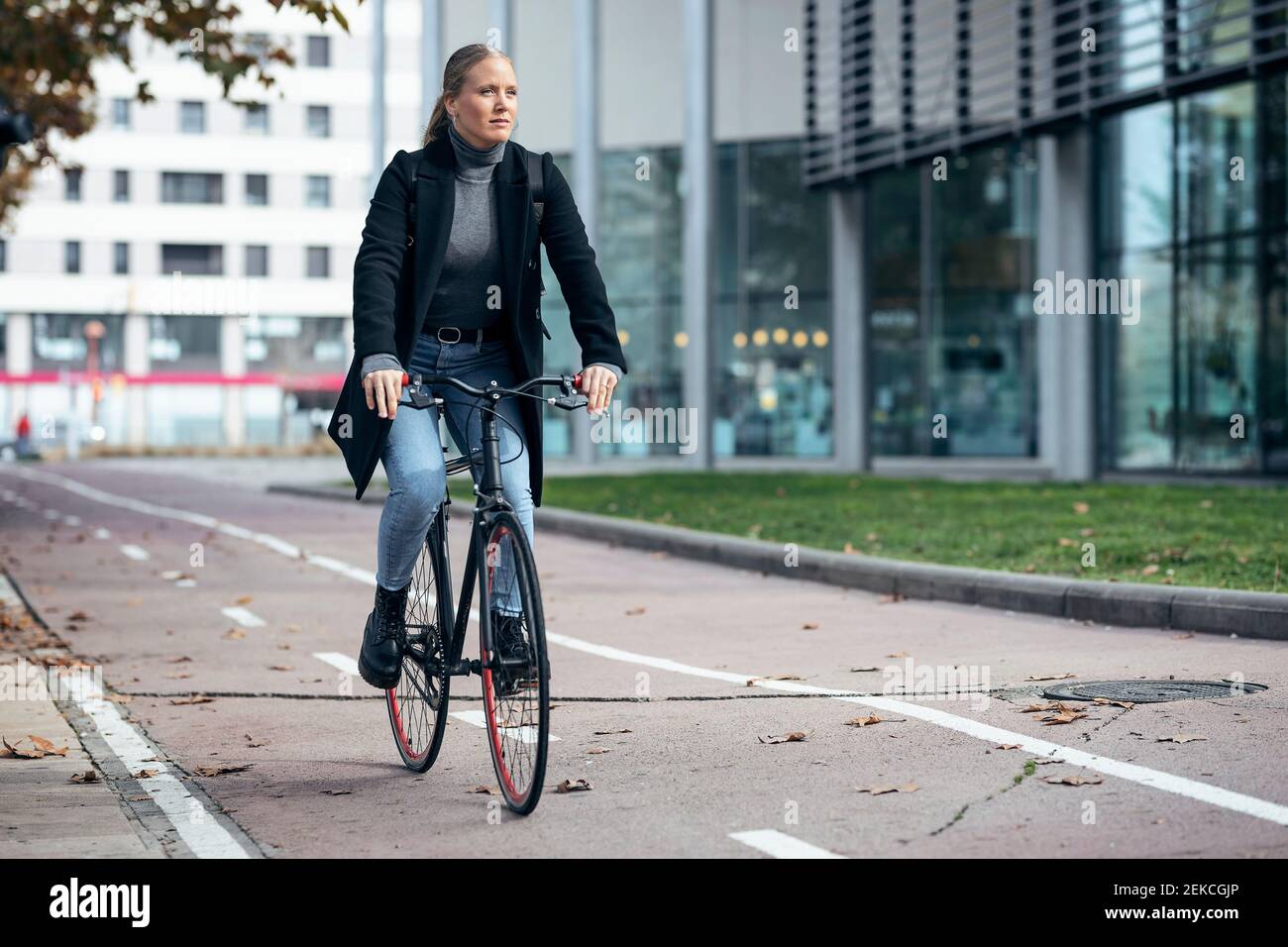 Woman doing cycling on road by modern building Stock Photo