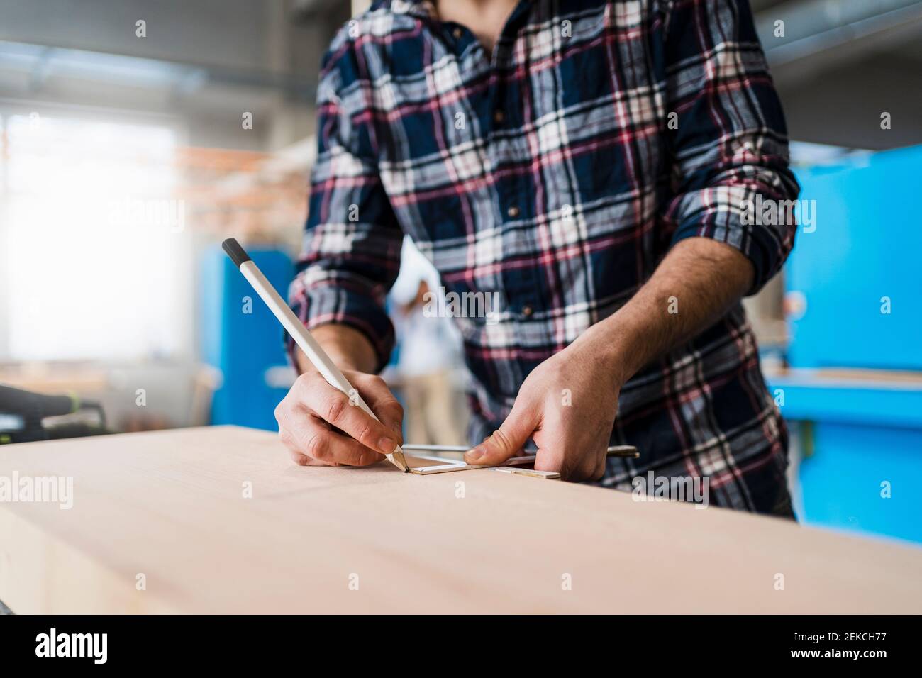 Manual worker measuring wood while working at industry Stock Photo