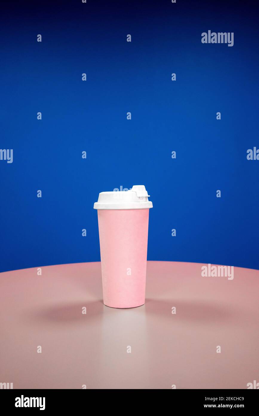 Reusable coffee cup on table against blue background Stock Photo