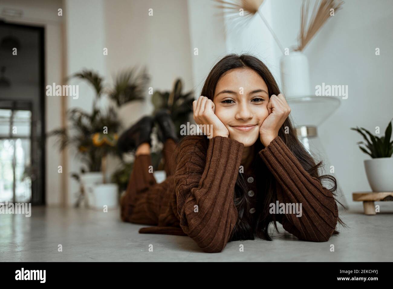 Smiling girl with head in hands lying on floor at home Stock Photo
