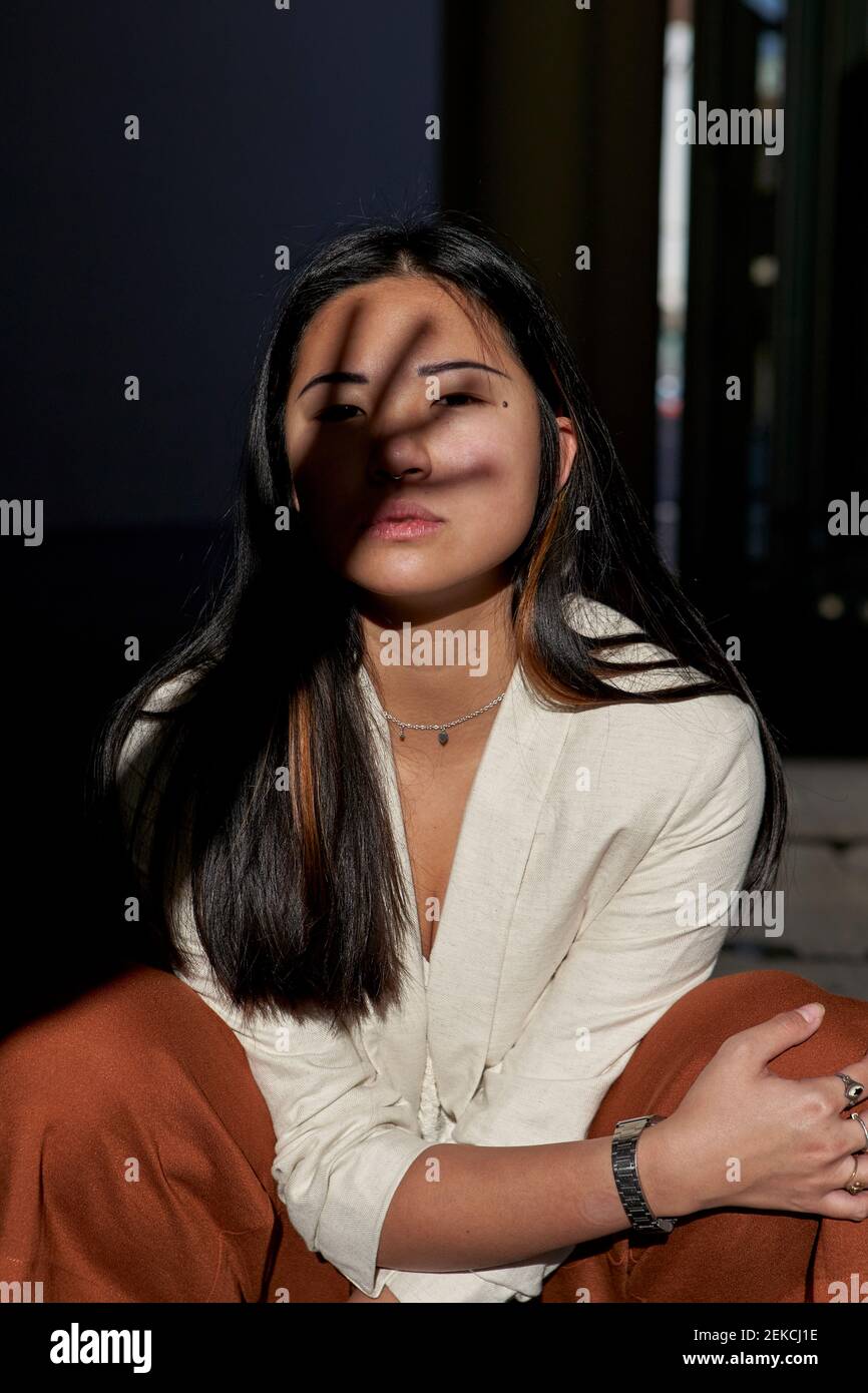 Beautiful young woman crouching with hand shadow on face Stock Photo