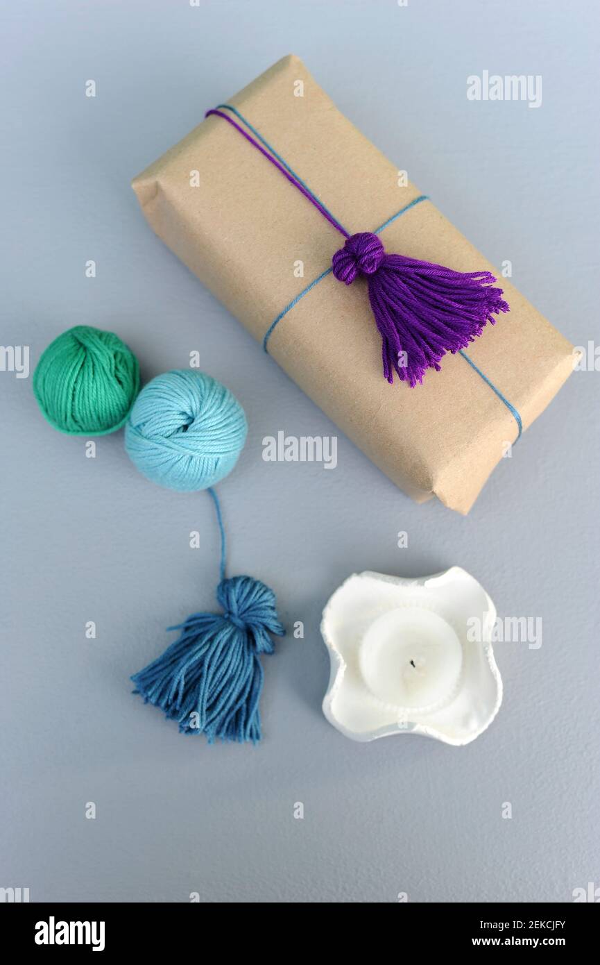Studio shot of balls of wool and wrapped gift with wool tassel Stock Photo