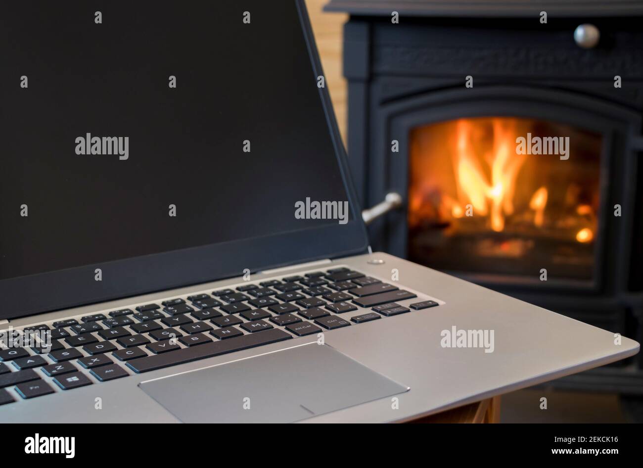 Closeup on laptop with fireplace in the background, cabin interior, cottage indoor, remote work, teleworking, Québec, Canada Stock Photo