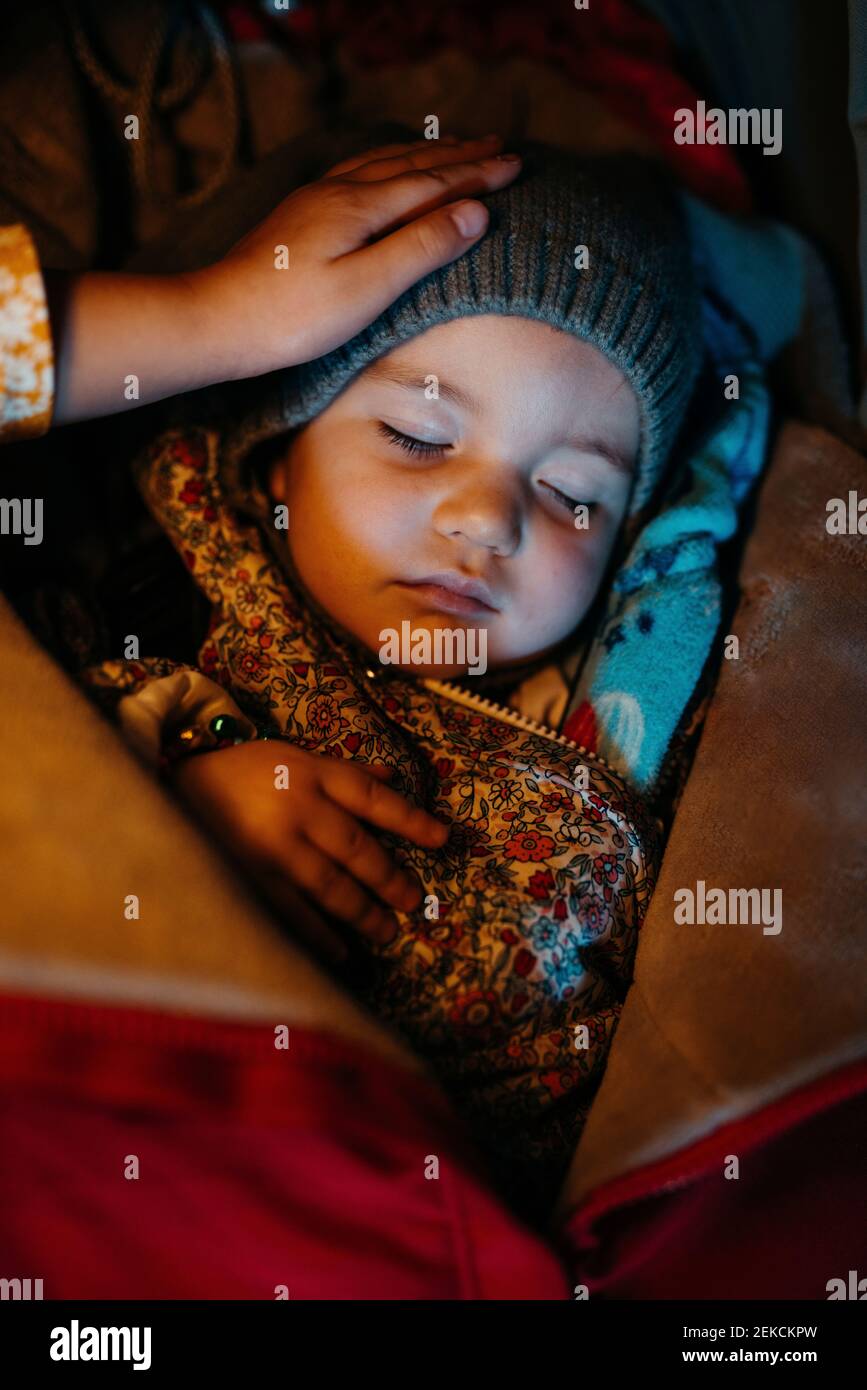 Sister admiring baby girl with warm clothing while sleeping during winter Stock Photo