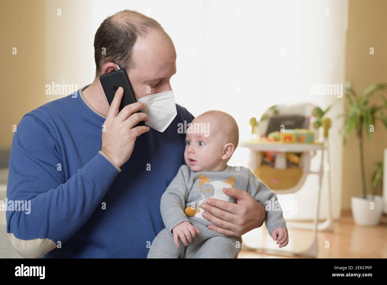 Businessman looking after newborn baby at home and teleworking Stock Photo