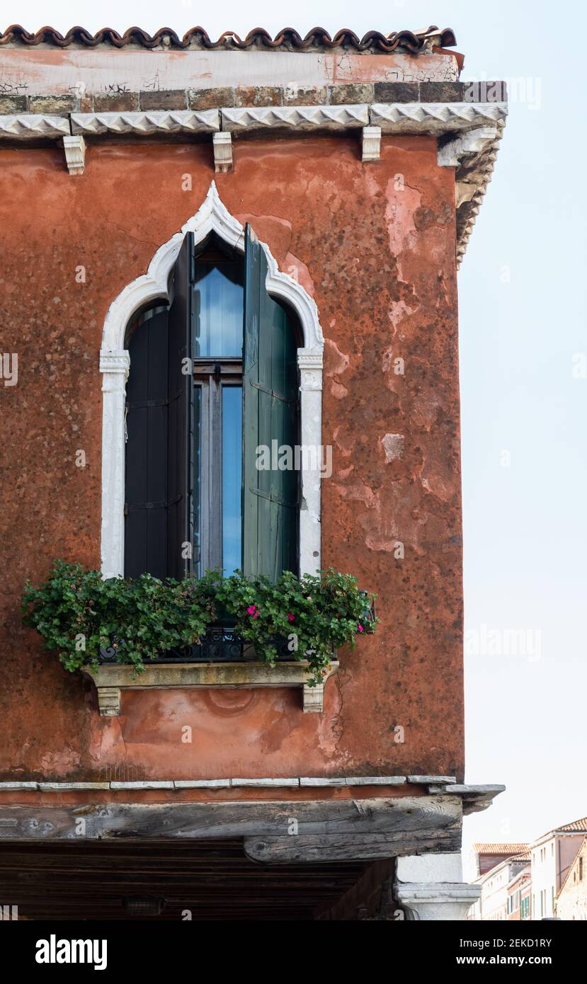 A beautiful gothic window with open shutters and a window box in an old terracotta building on the island of Murano, Venice, Italy Stock Photo