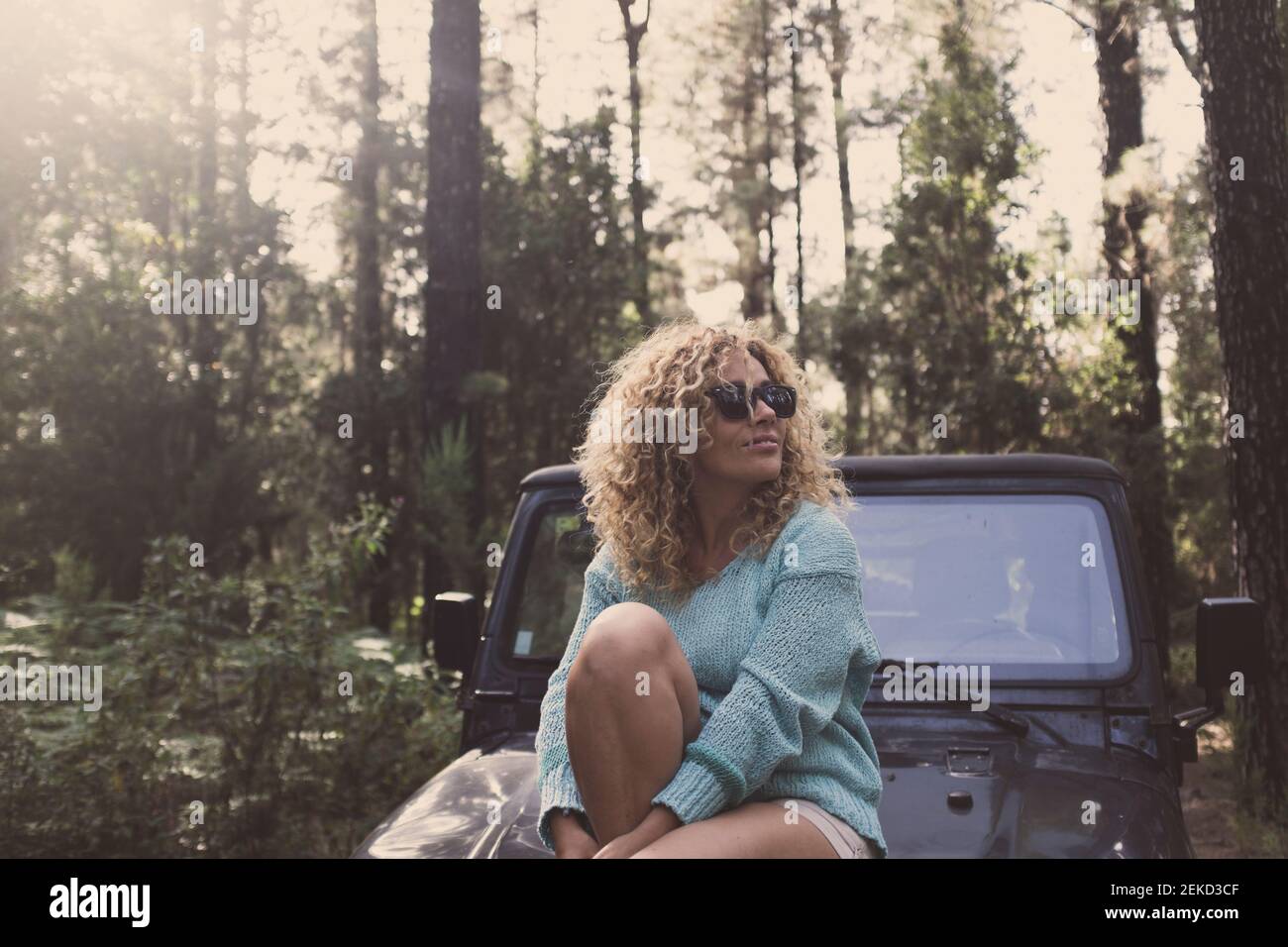 Cheerful happy lady enjoy freedom traveling by car in the forest - woman people in the woods alternative lifestyle in nature outdoor park leisure acti Stock Photo