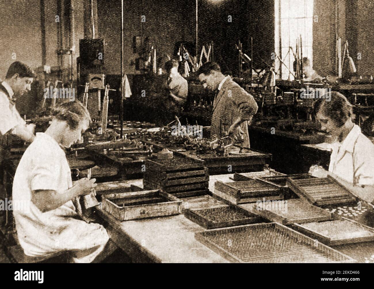 An early press photo showing workers at Kodak Camera factory in Britain checking camera lenses. Stock Photo