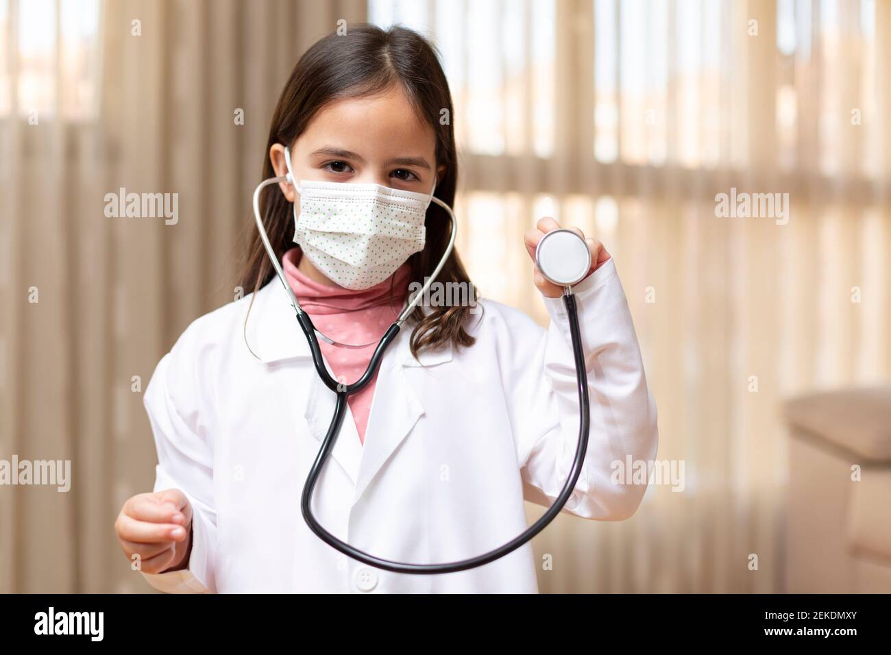 Portrait of little girl dressed as a doctor and medical mask using a ...