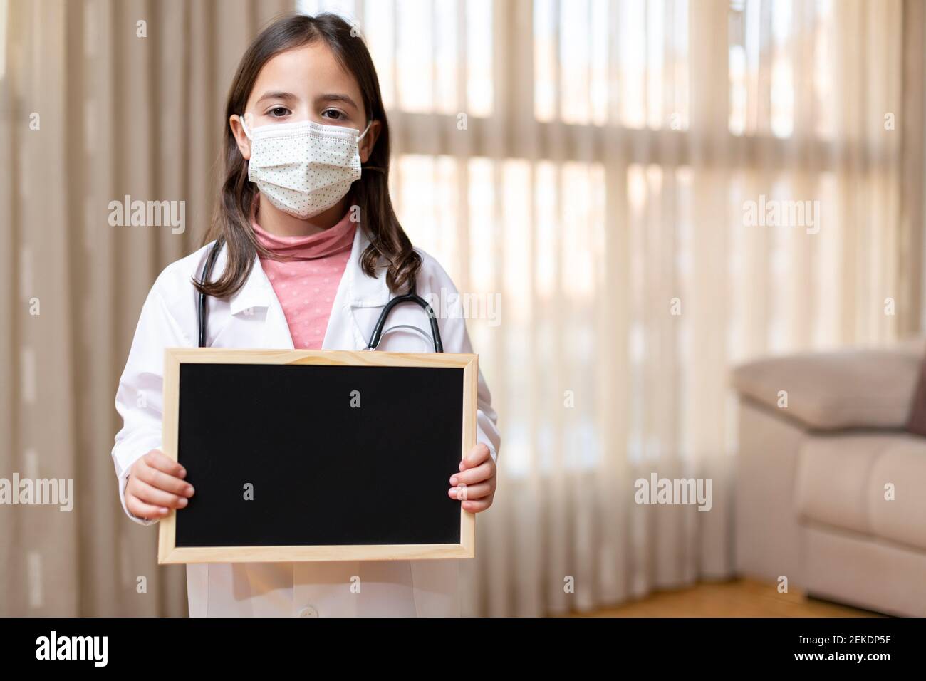 Little girl dressed as a doctor and medical mask holding with her hands ...