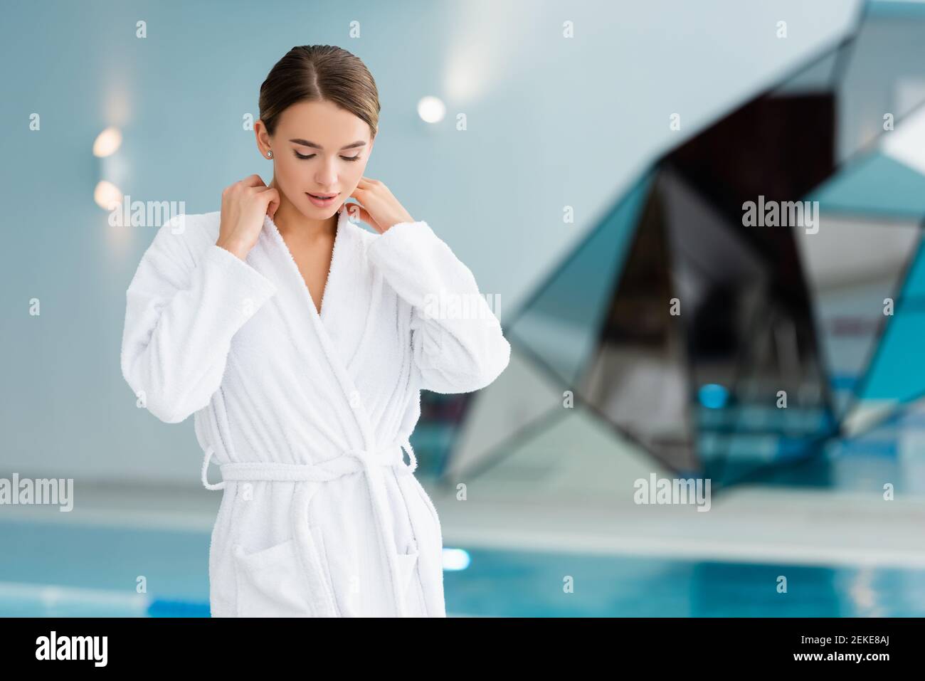 young woman adjusting white bathrobe in spa center Stock Photo
