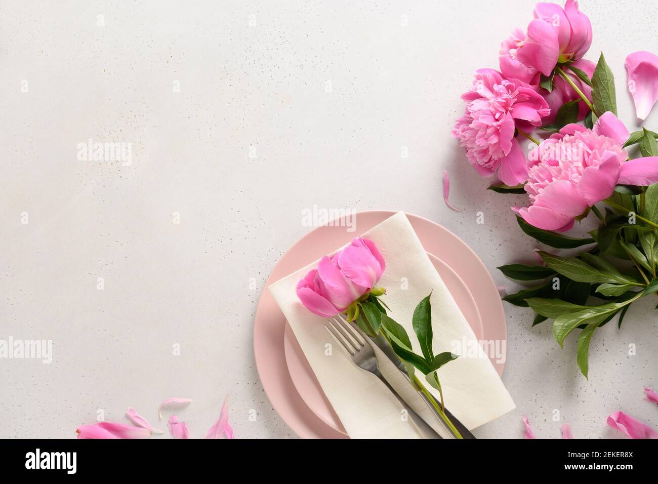 Spring romantic table setting with pink peony flowers on a white table. Stock Photo