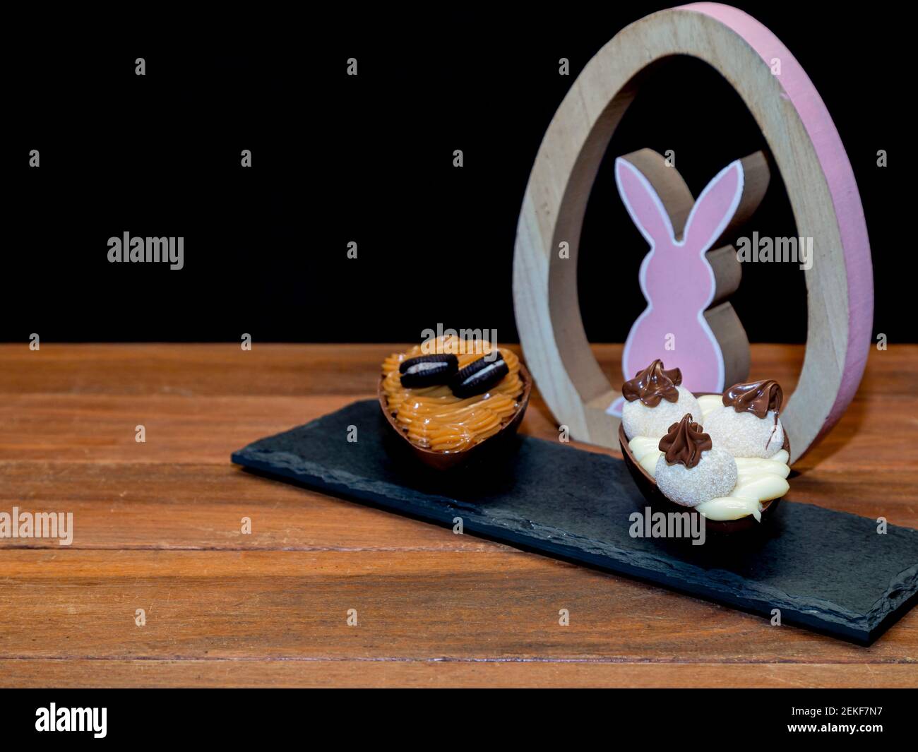 Chocolate easter eggs on top of black stone with wooden background ...