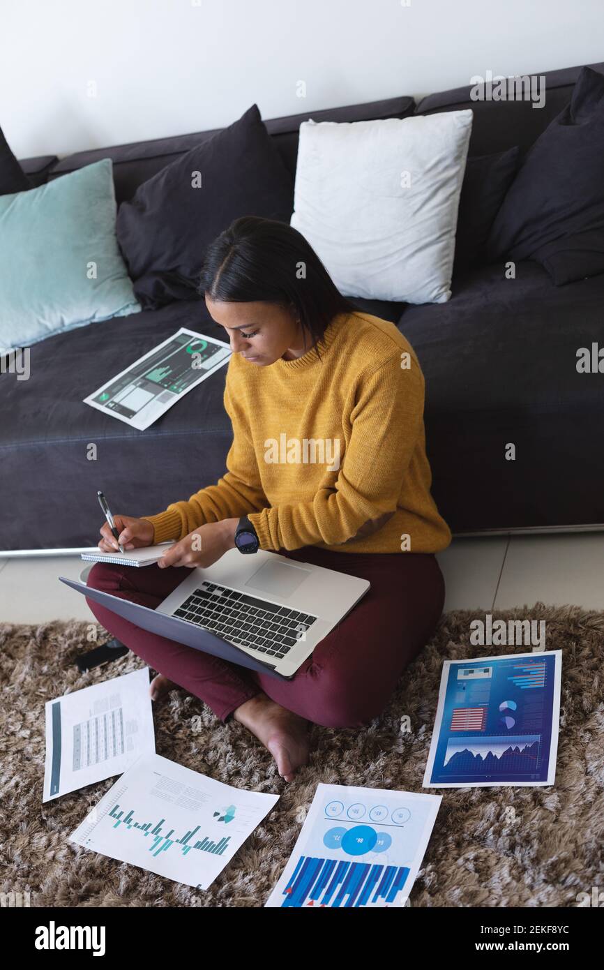 African american woman with laptop taking notes while working from home ...