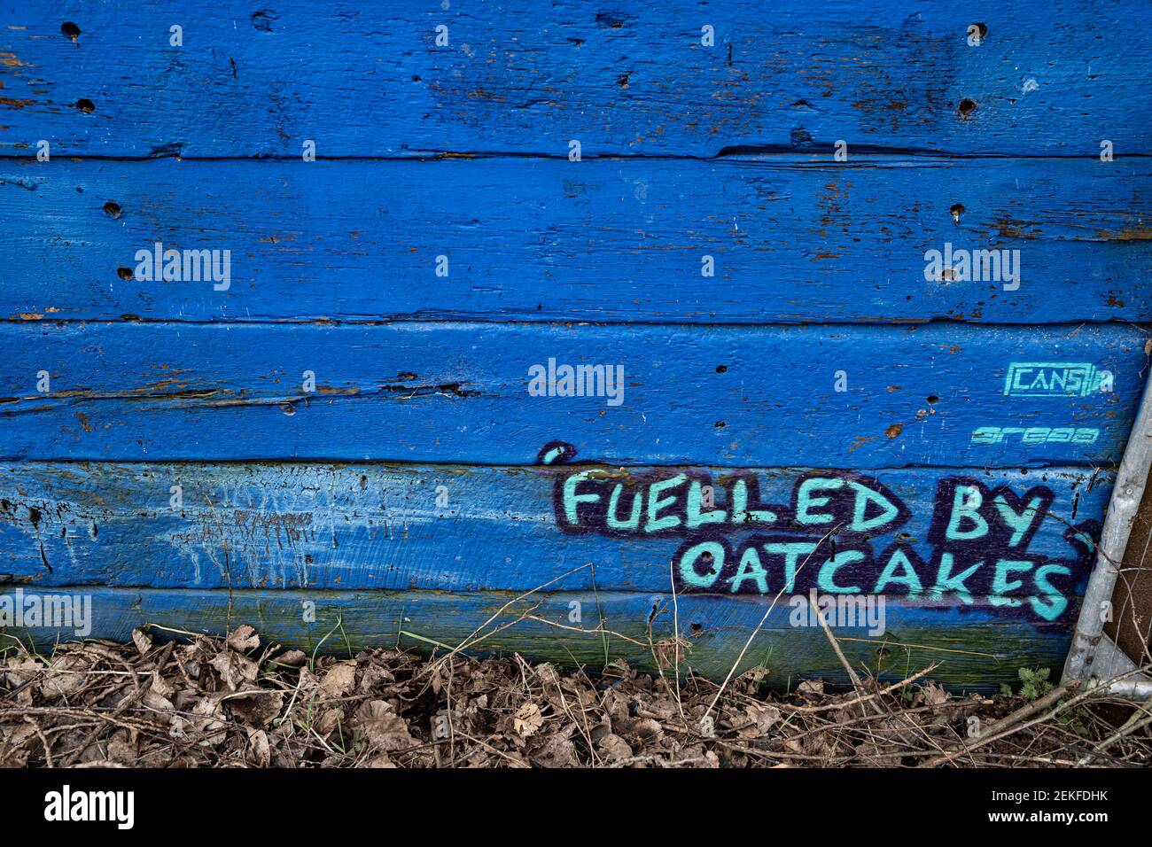 Graffiti on a fence by the Trent and Mersey canal, Middleport, Stoke-on-Trent, UK saying 'Fuelled by oatcakes' a local food of the area. Stock Photo