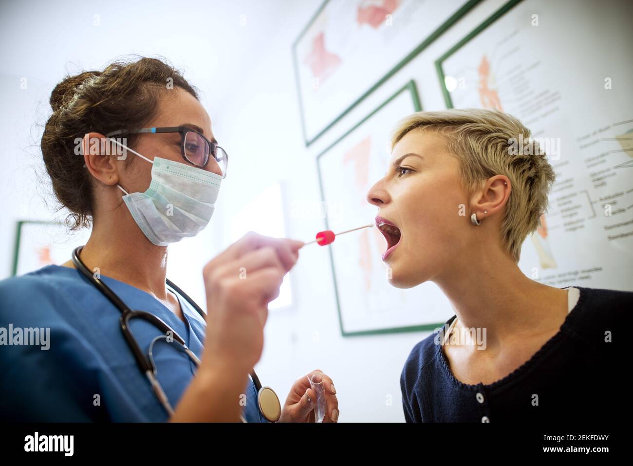 Side close view of female doctor specialist with face mask holding buccal cotton swab and test tube ready to collect DNA from the cells on the inside Stock Photo