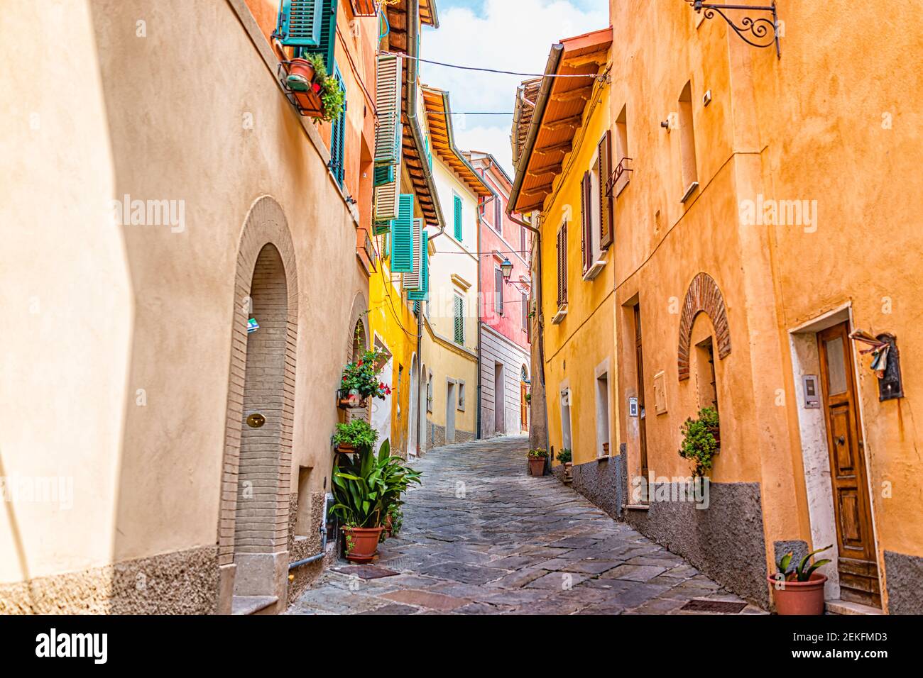 Chiusi, Italy narrow street alley in small historic medieval town village in Tuscany during sunny day with orange yellow multicolored colorful walls a Stock Photo