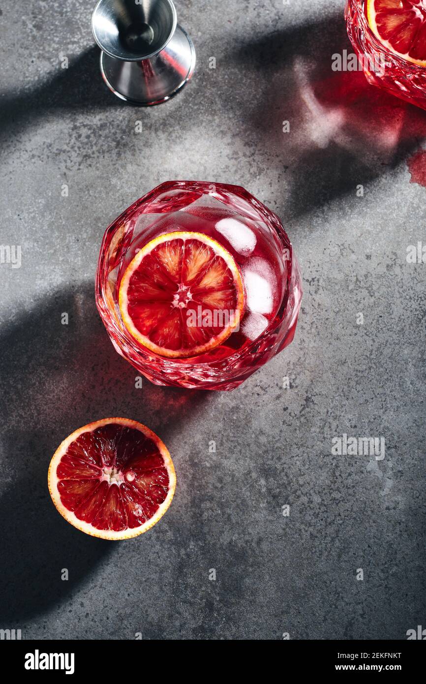 Negroni cocktail with ice cubes and blood orange on a dark gray stone background, top view. Stock Photo