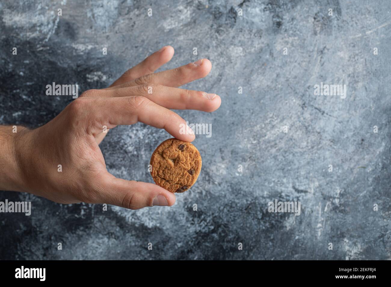 Man hand holding a delicious cookie on a gray background Stock Photo