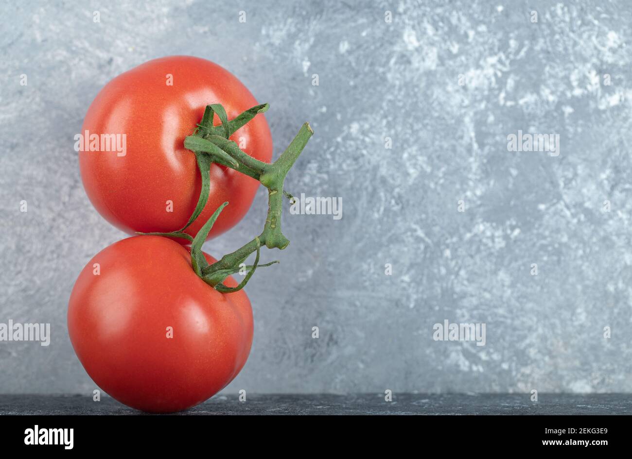 Two whole fresh juicy tomatoes on a gray background Stock Photo