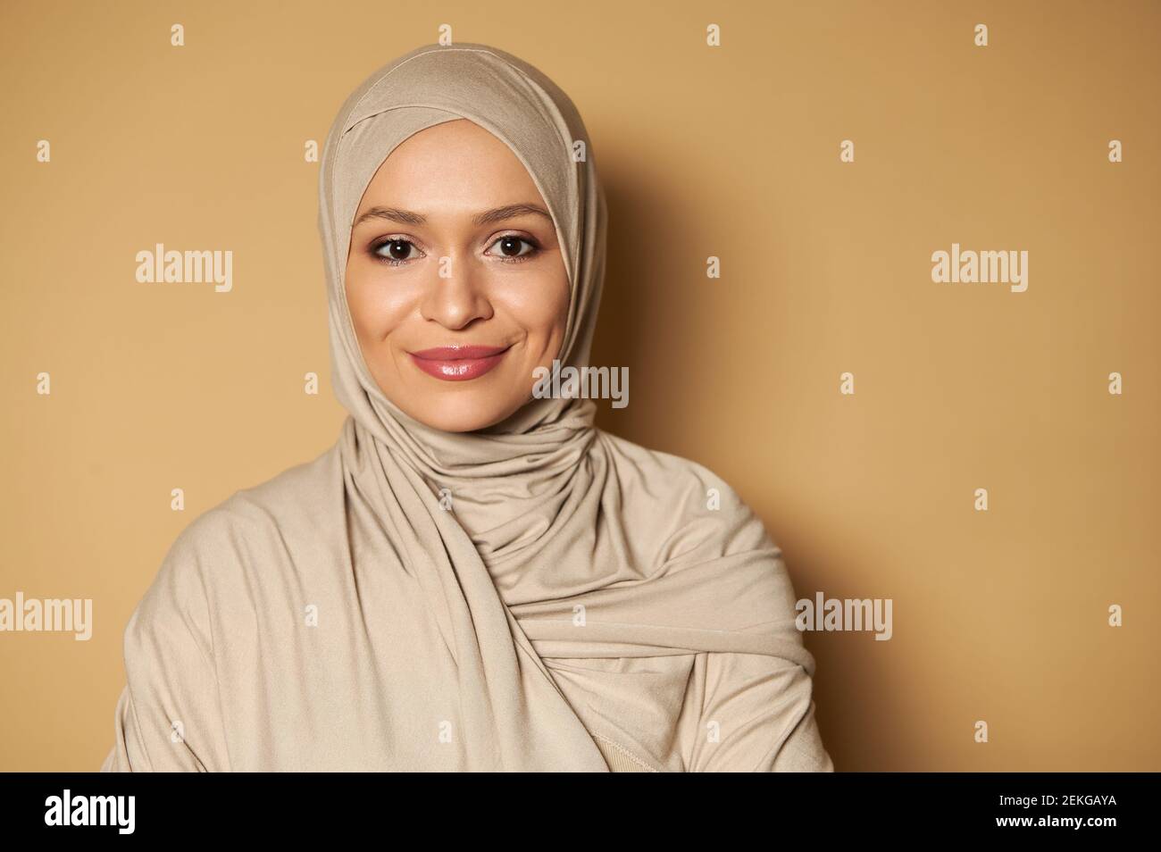Portrait of beautiful arab muslim woman wearing hijab. Strict formal outfit and elegant appearance. Islamic fashion. Beige background with copy space. Stock Photo