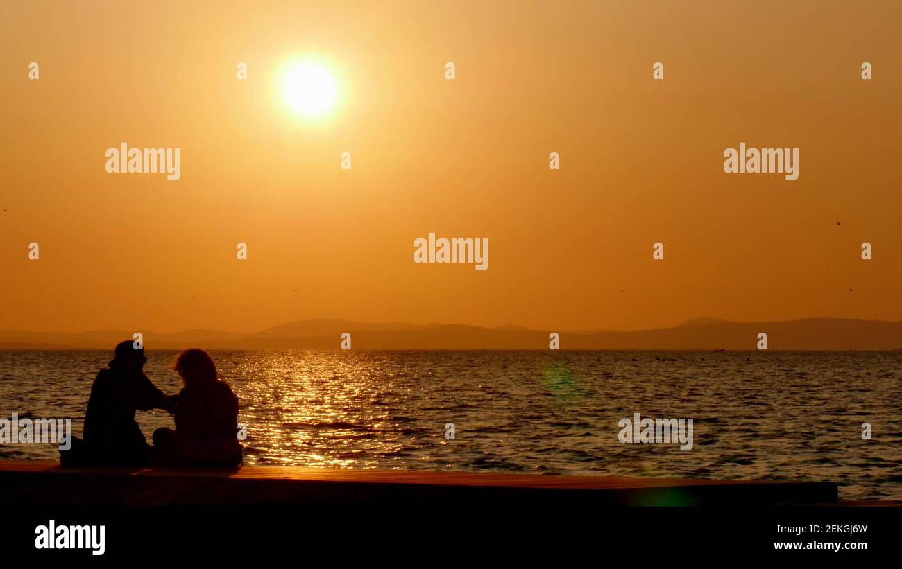 Silhouette of couple in love at sea in golden and beautiful sunset ...