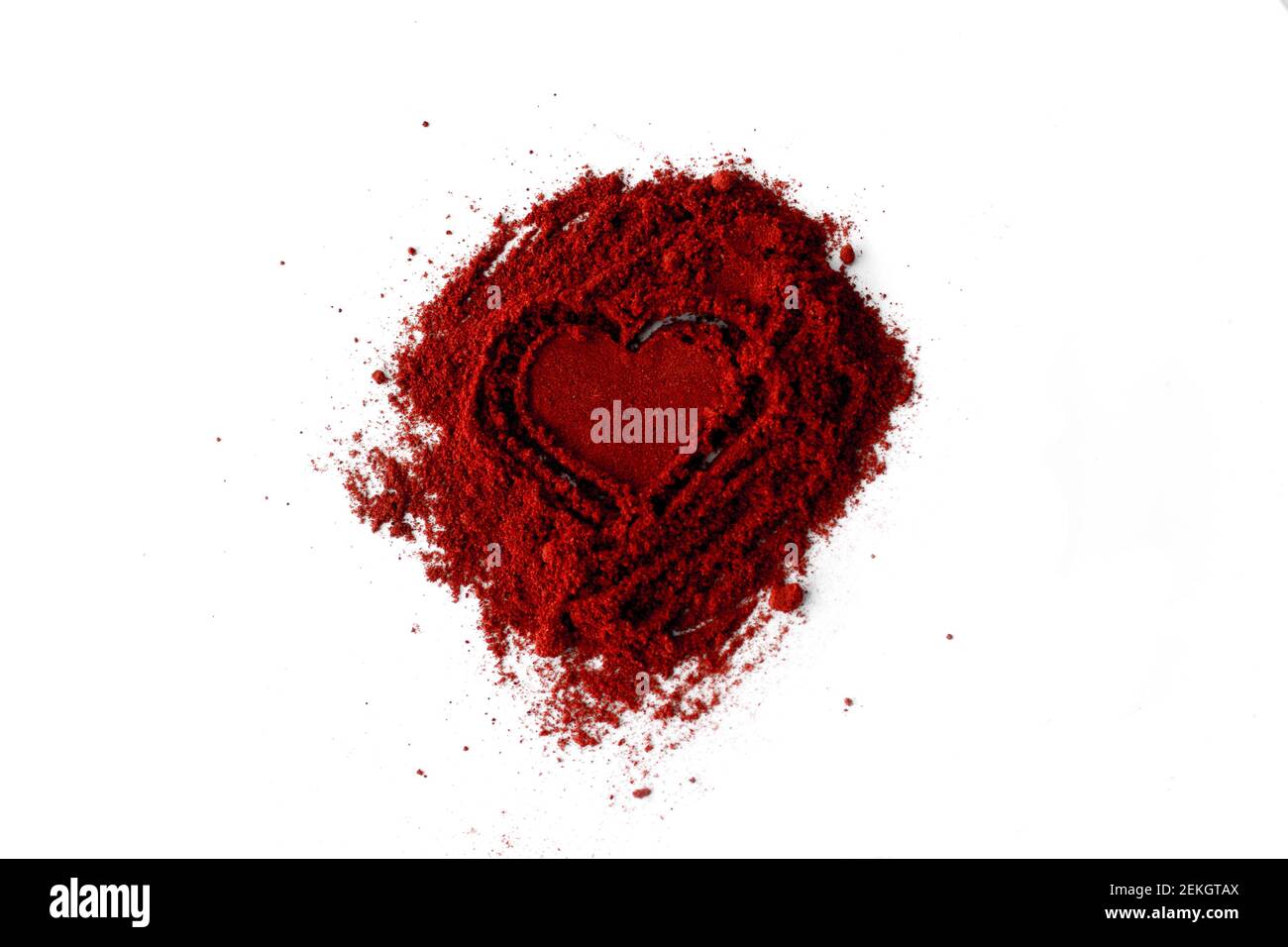 Close-Up Of Ground Red Chili Pepper Over White Background. Pile of ground Paprika isolated in heart  Stock Photo