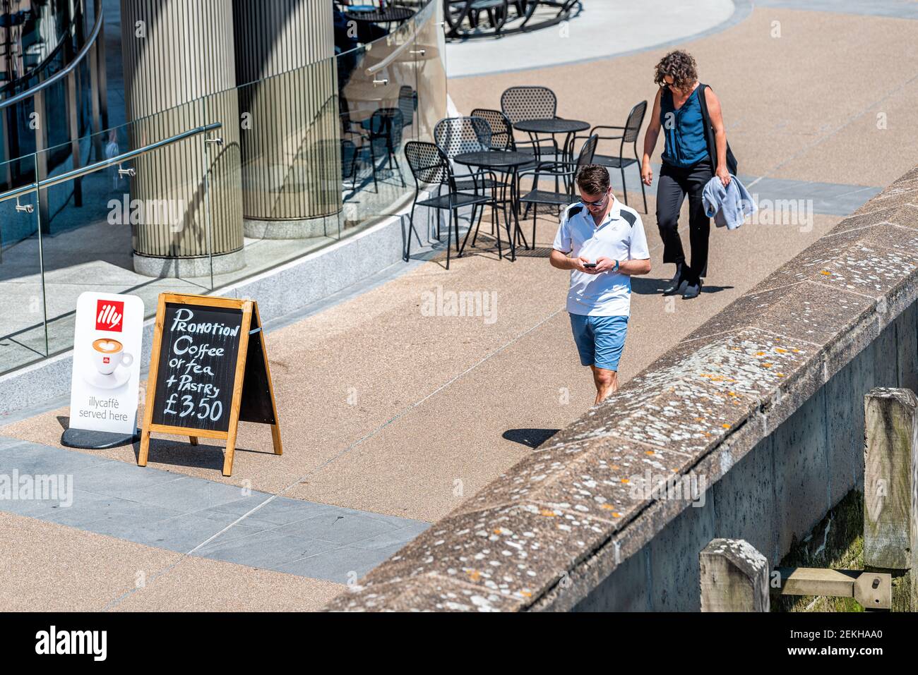 London, UK - June 25, 2018: High angle view of people walking on sidewalk in downtown by Illy cafe sign placard for coffee Stock Photo